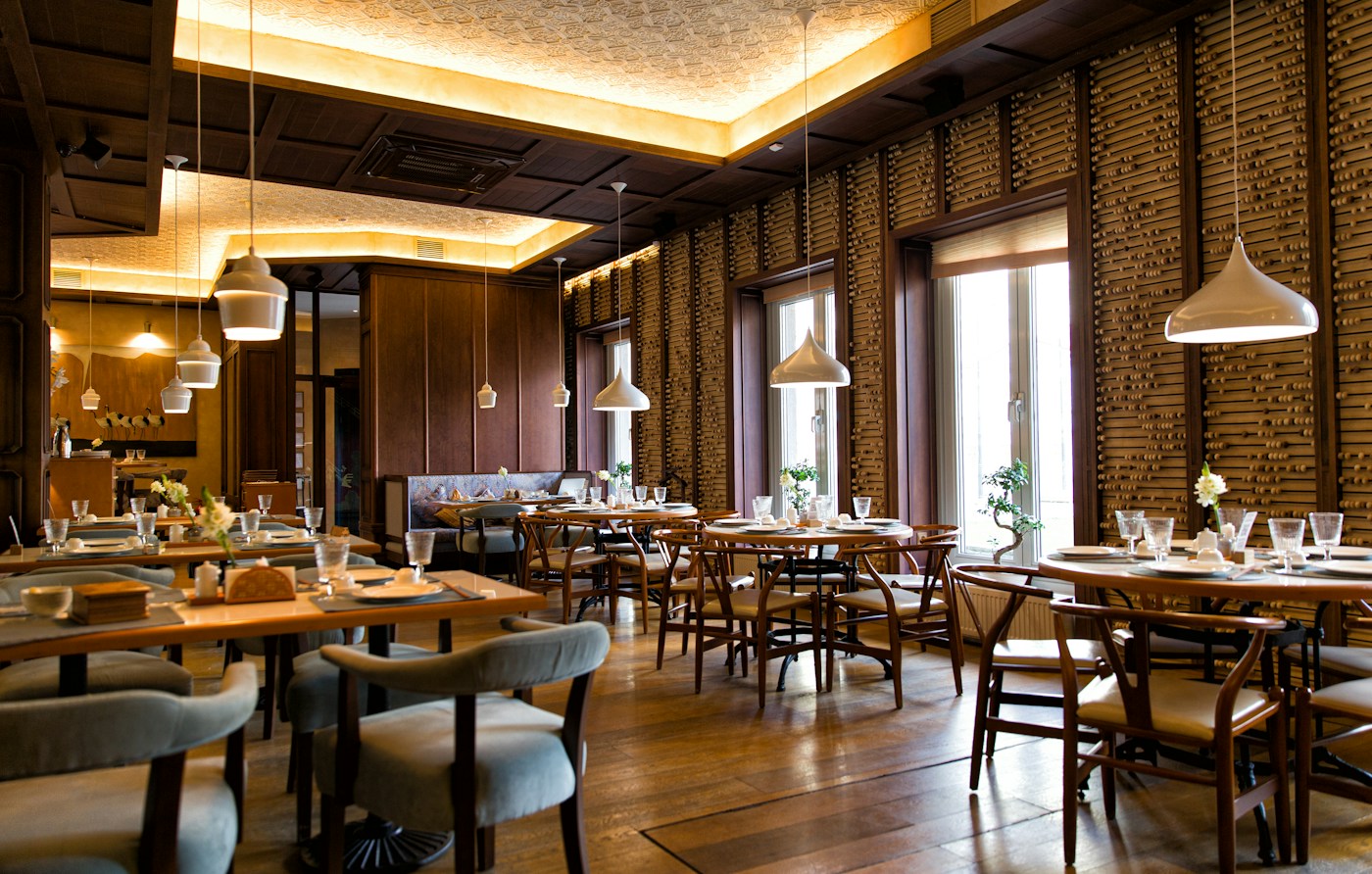 Ambiente acolhedor de restaurante, com mesas de madeira e luz natural